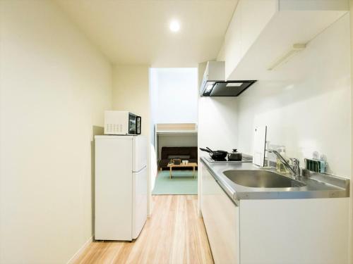 a white kitchen with a sink and a refrigerator at TRIP POD MINOSHIMA A in Fukuoka