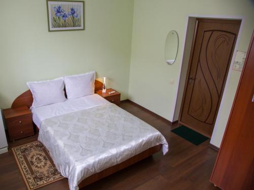 ニジニ・タギルにあるHotel Malakhitovayaの白いベッドと木製のドアが備わるベッドルーム1室が備わります。