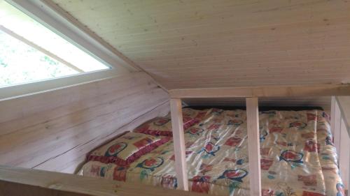 a bed in a tiny house with a window at Šeimos namelis - Mindūnų sodyba in Mindūnai