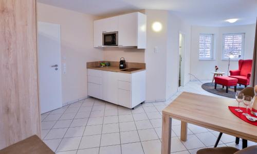 a kitchen and living room with a table and red chairs at Hotel Ochsen in Ammerbuch