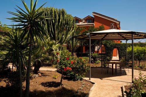 a patio with a table and an umbrella and some plants at B&B 7Cento Ulivi in Valderice