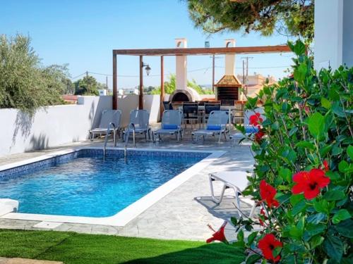 a swimming pool with chairs and a table and flowers at Villa Papagiorgio Luxury and Harmony in Gennadi