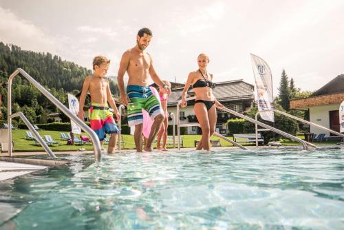 a group of people jumping into a swimming pool at Appartementanlage Thermenblick SKI IN & SKI OUT in Bad Kleinkirchheim