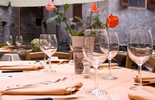 a table with wine glasses and a vase with flowers at Contrada Beltramelli in Villa di Tirano