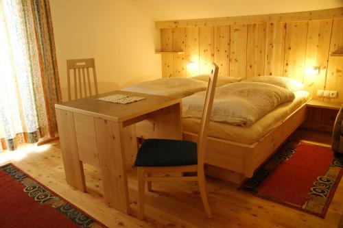 a bedroom with a bed with a desk and a chair at Haus Venetblick in Wenns
