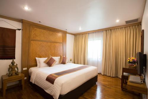 Habitación de hotel con cama grande y TV en The Tarntawan Hotel Surawong Bangkok en Bangkok