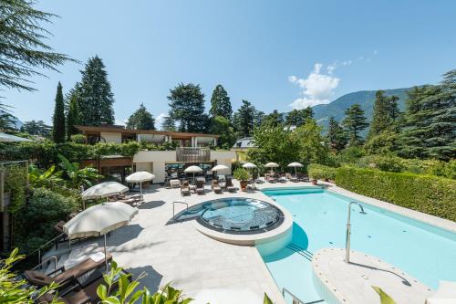 a swimming pool with chairs and a house at Hotel Mignon Meran Park & Spa in Merano