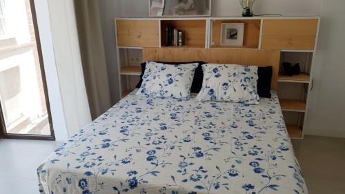 a bed with blue and white sheets and pillows at Vivienda con parking en el centro de Cartagena. in Cartagena