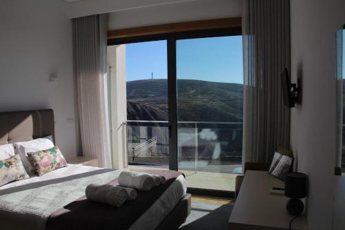 a bedroom with a bed and a couch and a large window at Hotel Rural da Freita in Arouca