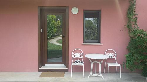 2 chaises et une table devant une maison rose dans l'établissement Lovely Cat's Room Urrunaga, à Urrúnaga