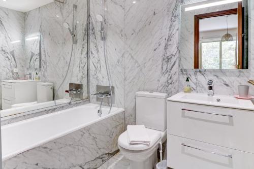 La salle de bains blanche est pourvue d'une baignoire, de toilettes et d'un lavabo. dans l'établissement PROMENADE HOLIDAY - PALATIN PROMENADE, à Nice
