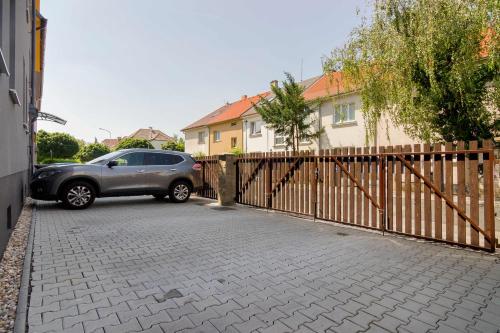 a car parked in a driveway next to a fence at APT with sunny garden Prague by Michal&Friends in Prague