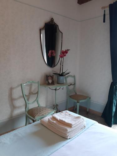 a bedroom with a bed with a mirror and two chairs at Il mulino di Aurora in Dosso del Liro
