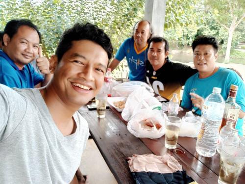 a group of men sitting around a wooden table at ชลลดา ริเวอร์ โฮมสเตย์ แก่งกระจาน in Ban Wang Malako