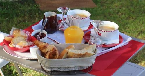einen Tisch mit einem Frühstück mit Brot und Orangensaft in der Unterkunft Écuries de Laramière in Laramière