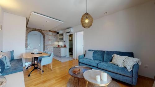 a living room with a blue couch and a table at Riva Apartments in Split