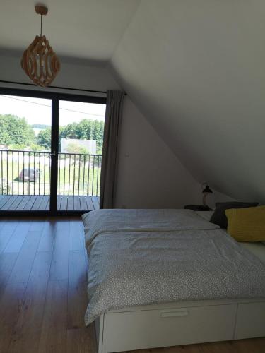 a bedroom with a bed and a large window at Grzybowo Dom wakacyjny in Grzybowo