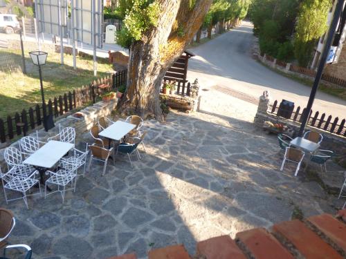 eine Gruppe von Tischen und Stühlen neben einem Baum in der Unterkunft Hotel La Vega in Alcalá de la Selva