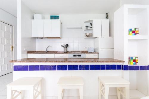 a kitchen with white cabinets and blue accents at Apartamentos Cabrera in Puerto del Carmen