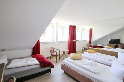 Habitación con 4 camas, cortinas rojas y mesa. en Hotel Kick en Rauenberg