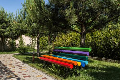 a colorful bench sitting in the grass next to a tree at Kompleks Otdykha Elki-Palki in Odesa