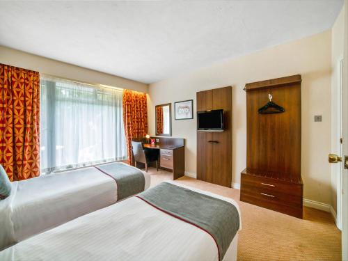 a hotel room with two beds and a desk at The Bridge House Hotel in Reigate