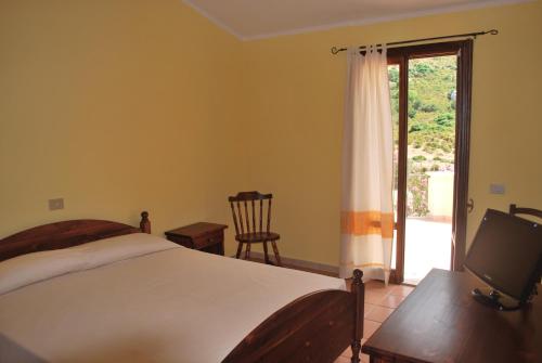 a bedroom with a bed and a sliding glass door at Punto Di Ristoro Uttolo in Baunei