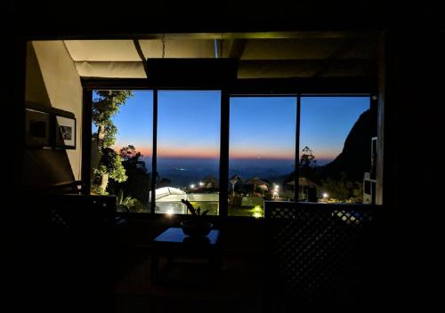 a room with a large window with a view of the sunset at EKHO Ella - A Divine View of Ella Gap in Ella
