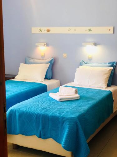 two beds in a room with blue sheets at Elena Studios & Apartments in Piso Livadi