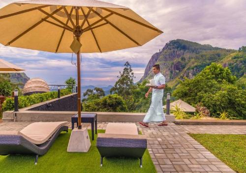 a man standing on a patio with an umbrella at EKHO Ella - A Divine View of Ella Gap in Ella
