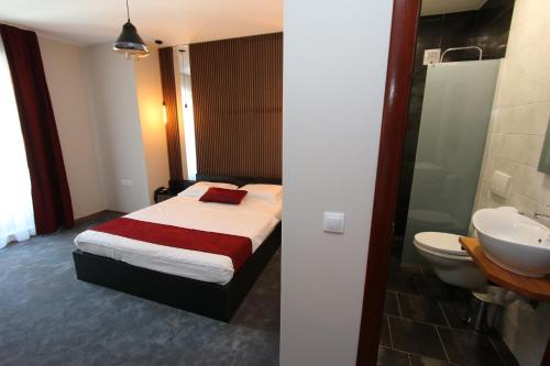 1 dormitorio con 1 cama y baño con lavamanos en Prior Hotel en Prizren