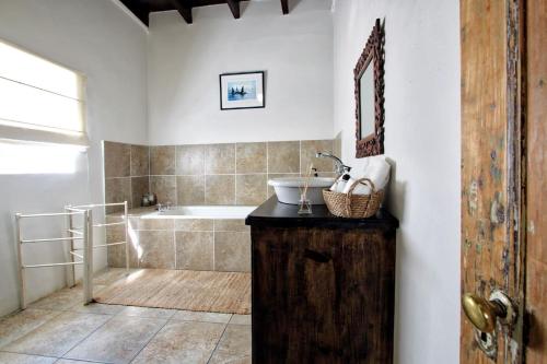 a bathroom with a sink and a bath tub at The Townhouse in Graaff-Reinet
