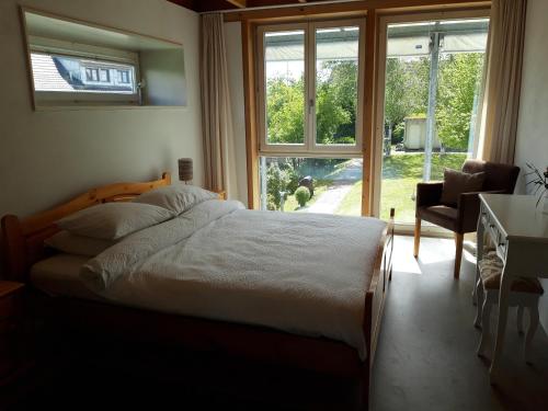 ein Schlafzimmer mit einem Bett, einem Stuhl und einem Fenster in der Unterkunft B&B 25 in Münchwilen