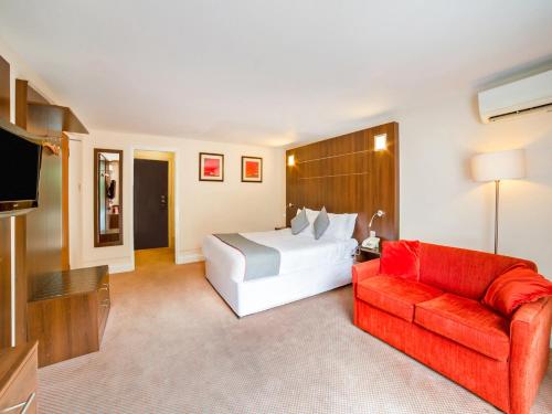 a hotel room with a bed and a red couch at The Bridge House Hotel in Reigate