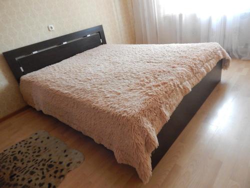 a bed with a brown blanket on a wooden floor at Apartment 18 Microrayon in Zhlobin