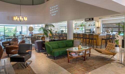 a lobby with a green couch and a bar at Lily & Bloom Boutique Hotel in Tel Aviv