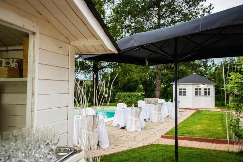 a patio with white tables and chairs and a pool at Villa Sequoia in Leinì