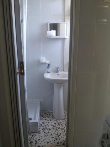 a white bathroom with a sink and a toilet at Monolocale in via San Sebastiano Ficarra in Ficarra