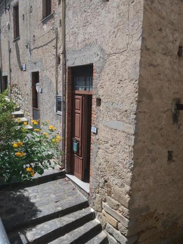 a stone building with a brown door and stairs at Monolocale in via San Sebastiano Ficarra in Ficarra