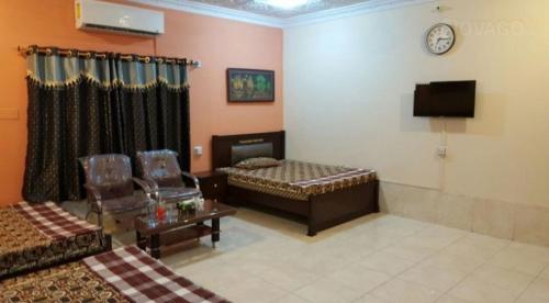 a living room with two beds and a clock on the wall at Tourist Lodge Guest House in Kalar Goth