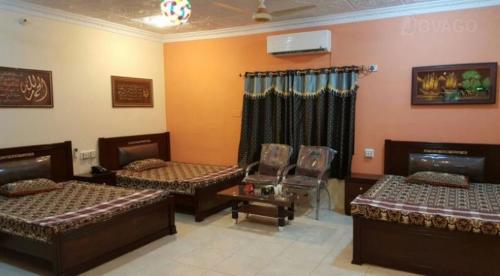 a room with three beds and chairs in it at Tourist Lodge Guest House in Kalar Goth