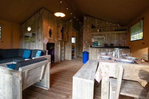 una sala da pranzo con pareti in legno, tavolo e sedie di Lapwing Safari Tent a Cheltenham