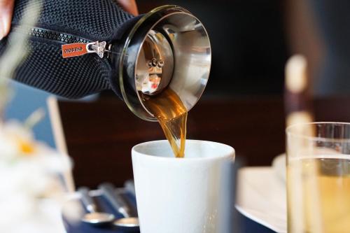 Una persona está sirviendo café en una taza. en Hôtel & Restaurant Sodade, en Chaudes-Aigues