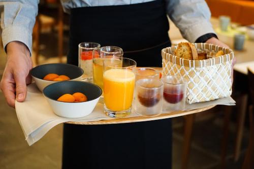 una persona con una bandeja de comida y bebida en Hôtel & Restaurant Sodade, en Chaudes-Aigues