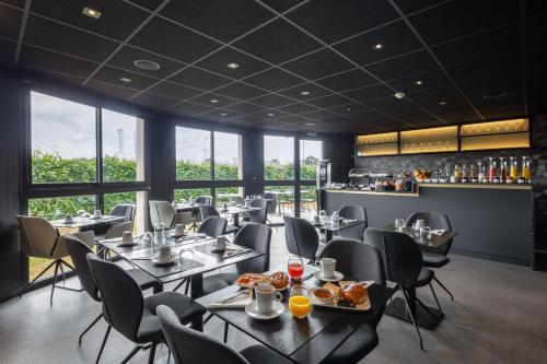 un restaurant avec des tables et des chaises ainsi qu'un bar dans l'établissement Hotel l'Ortega Rennes Aeroport, à Saint-Jacques-de-la-Lande