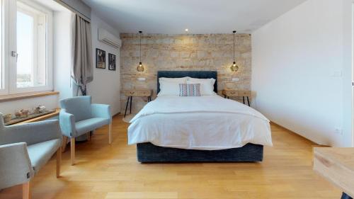 a bedroom with a large bed and a blue chair at Riva Apartments in Split