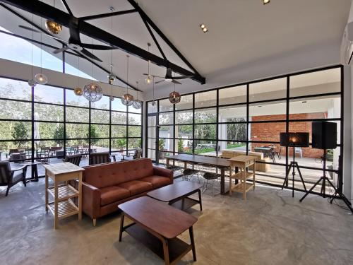 a living room with a couch and tables and windows at The Rubber Escape, Melaka in Melaka