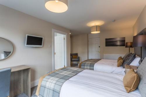 a hotel room with two beds and a tv at Carlogie House in Carnoustie