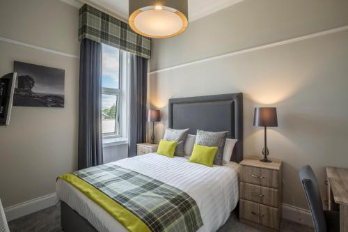 a bedroom with a bed with yellow pillows and a window at Carlogie House in Carnoustie