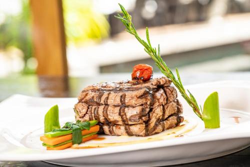 a piece of steak on a white plate with vegetables at Savoy Seychelles Resort & Spa in Beau Vallon